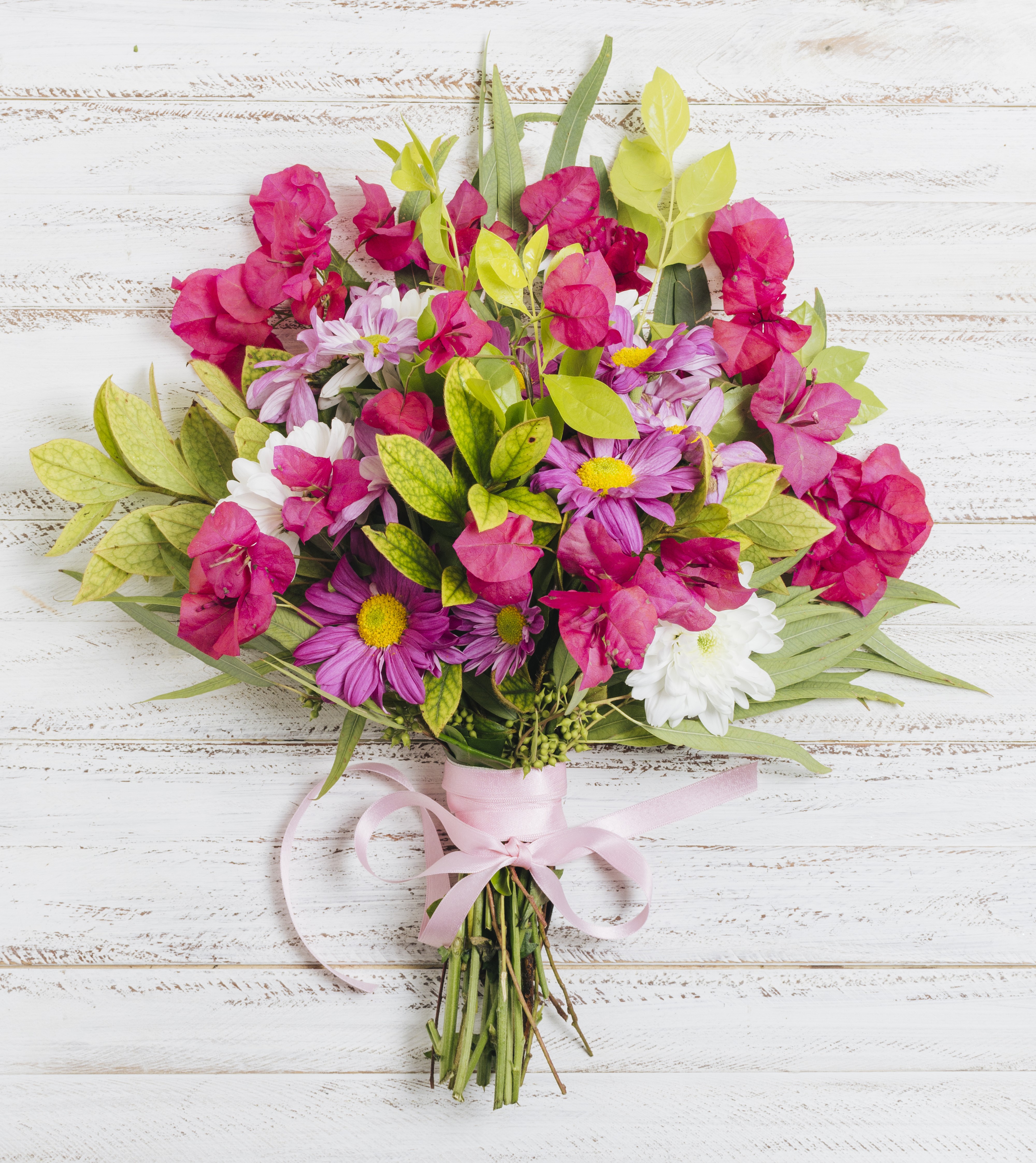 colorful flower bouquet tied with pink ribbon wooden desk